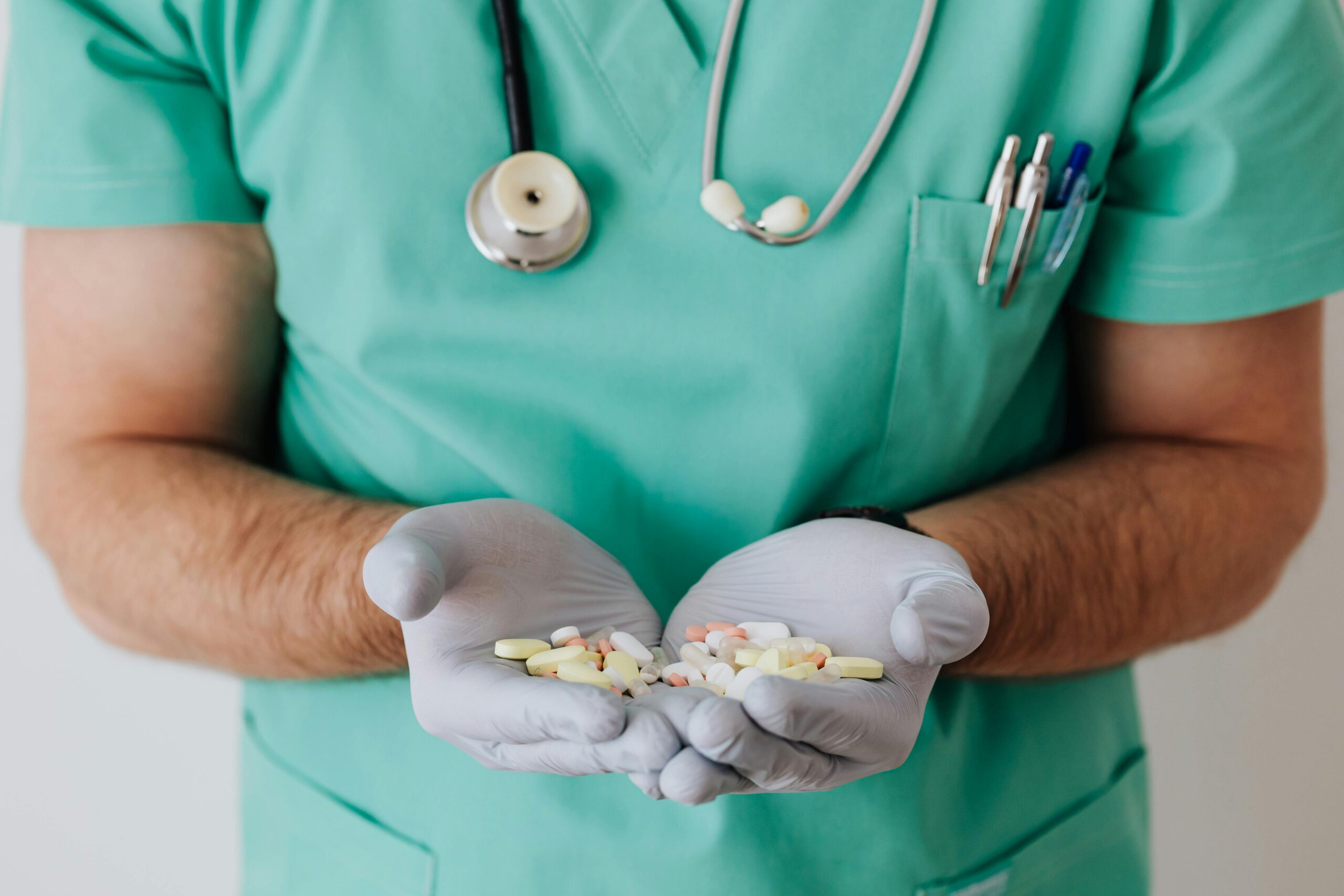 Crop unrecognizable medical worker in rubber disposable gloves holding in hands assorted pills